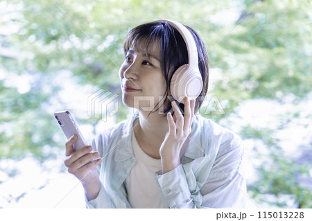 ヘッドホンでスマホの音楽を聴く若い女性 ヘッドホンでスマホの音楽を聴く若い女性 115013228