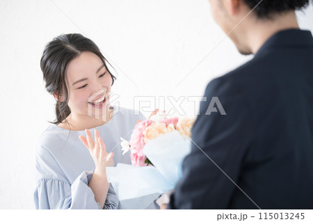 花束のプレゼントを受け取る若い女性と贈る男性の顔無し 花束のプレゼントを受け取る若い女性と贈る男性の顔無し 115013245