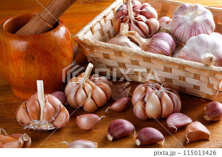 Close Up Raw, Fresh Garlic Cloves and Bulbs on Rustic basket Wooden Table Close Up Raw, Fresh Garlic Cloves and Bulbs on Rustic basket Wooden Table 115013426
