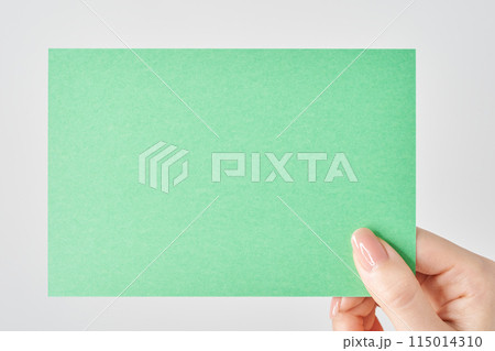 緑色の紙を持つ女性の手元 緑色の紙を持つ女性の手元 115014310