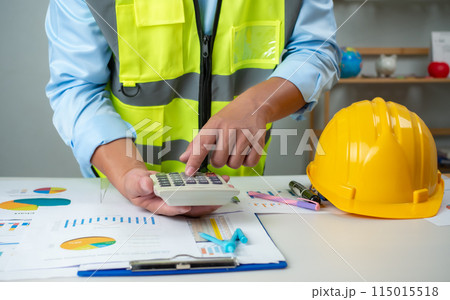 A foreman sits at a desk in an office, Calculating costs, Planning construction, Calculating structures, Planning and calculating project construction costs, Project presentation plan. A foreman sits at a desk in an office, Calculating costs, Planning construction, Calculating structures, Planning and calculating project construction costs, Project presentation plan. 115015518