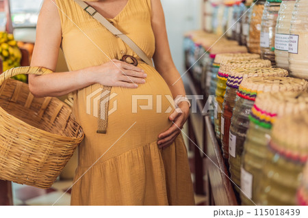 A pregnant woman is at a fruit stand in a grocery store Pregnant woman buying organic vegetables and fruits at Mexican style farmers market A pregnant woman is at a fruit stand in a grocery store Pregnant woman buying organic vegetables and fruits at Mexican style farmers market 115018439