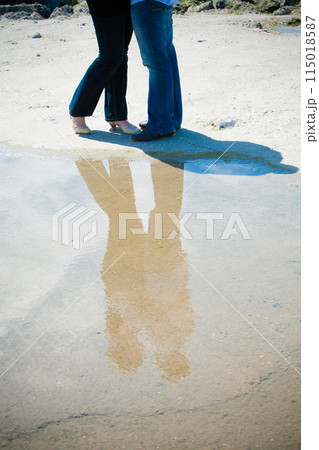 A sandy beach reflects a couples feet, symbolizing romantic togetherness in an outdoor setting A sandy beach reflects a couples feet, symbolizing romantic togetherness in an outdoor setting 115018587