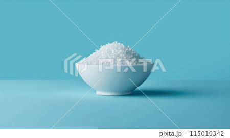 White bowl filled with sugar substitute crystals on a light blue background. Ideal for low-calorie and sugar-free diets 115019342
