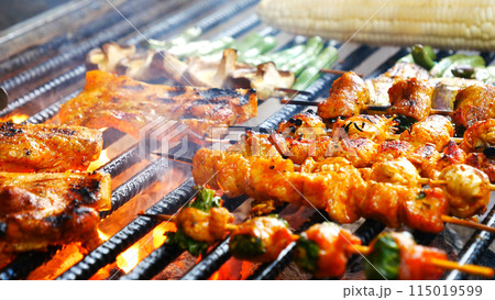 BBQ Barbecue grilled meat stick on fire flame with hot charcoal cooking outside. Beef grilling picnic outdoor with smoke bacon spicy sausage for party. Grill pork bbq on fire flame 115019599
