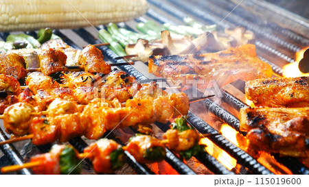 BBQ Barbecue grilled meat stick on fire flame with hot charcoal cooking outside. Beef grilling picnic outdoor with smoke bacon spicy sausage for party. Grill pork bbq on fire flame BBQ Barbecue grilled meat stick on fire flame with hot charcoal cooking outside. Beef grilling picnic outdoor with smoke bacon spicy sausage for party. Grill pork bbq on fire flame 115019600