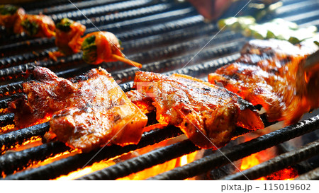 BBQ Barbecue grilled meat stick on fire flame with hot charcoal cooking outside. Beef grilling picnic outdoor with smoke bacon spicy sausage for party. Grill pork bbq on fire flame 115019602