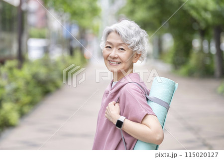 ヨガマットを持ったシニア女性　カメラ目線　笑顔 115020127
