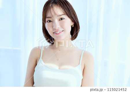 部屋の中でレースカーテン越しにくつろぐ女性 115021452