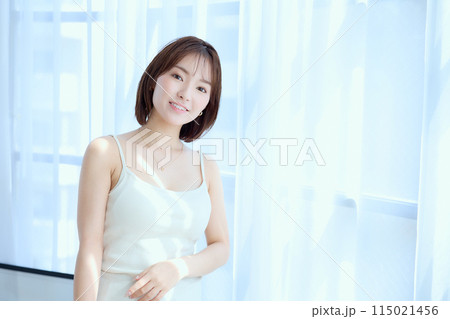 部屋の中でレースカーテン越しにくつろぐ女性 115021456