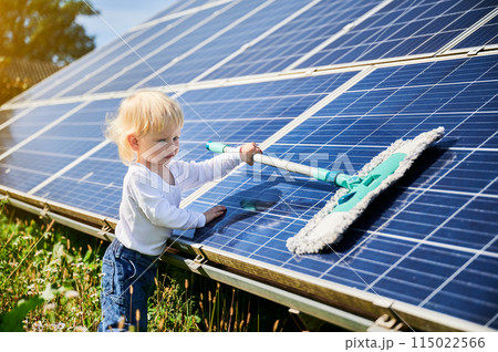 Little kid learning how to clean solar panel. Young boy learning how to care about solar station. Concept of young generation and green energetic. 115022566