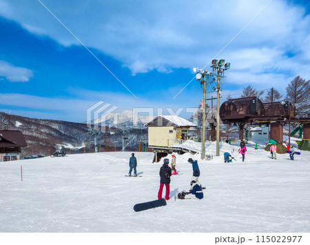 遠くに妙高山を望む晴天のゲレンデで滑走準備をするスノーボーダー達 (長野県、斑尾高原) 115022977