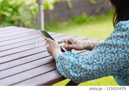 テラス席でスマホを使用する若い女性 テラス席でスマホを使用する若い女性 115023479