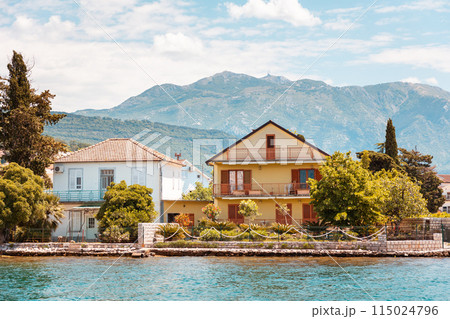 Beautiful Mediterranean house among plants and trees by sea. Mountains in background. Summer vacation in vintage hotel 115024796