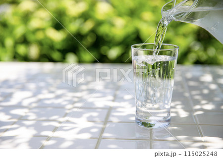 水を注ぐ　木陰のテーブルで冷たいミネラルウォーターを飲む 115025248
