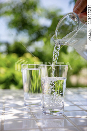 水を注ぐ　木陰のテーブルで冷たいミネラルウォーターを飲む 115025254
