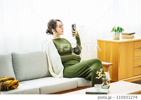 自宅のソファーでスマホを見る女性 115031274