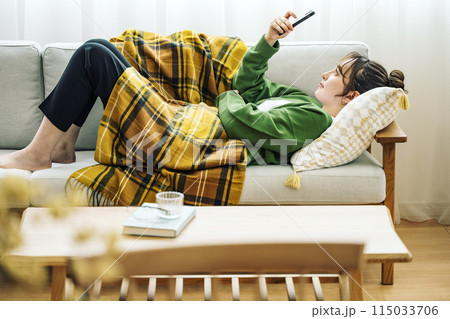自宅のソファーでスマホを見る女性 115033706