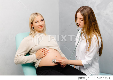 Female doctor using stethoscope examining pregnant woman in clinic. Medical exam pregnant woman 115035504