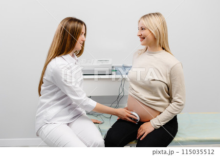 Doctor prepares a pregnant woman for checking fetal heartbeat by fetal monitoring. 115035512