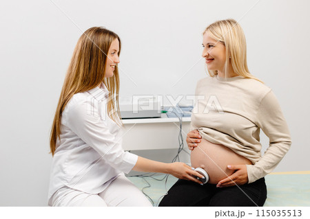 Doctor prepares a pregnant woman for checking fetal heartbeat by fetal monitoring. Doctor prepares a pregnant woman for checking fetal heartbeat by fetal monitoring. 115035513