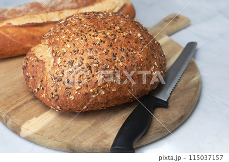 Round freshly oat baked bread on a cutting board. Round freshly oat baked bread on a cutting board. 115037157
