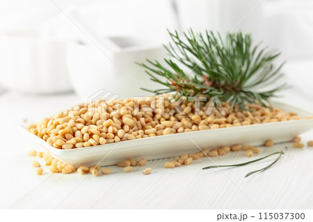 Peeled pine nuts on a white wooden table. Peeled pine nuts on a white wooden table. 115037300