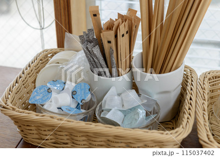 コーヒー用品、カゴに入ったコーヒーフレッシュ、ガムシロップ、スティックシュガー、木のマドラー コーヒー用品、カゴに入ったコーヒーフレッシュ、ガムシロップ、スティックシュガー、木のマドラー 115037402