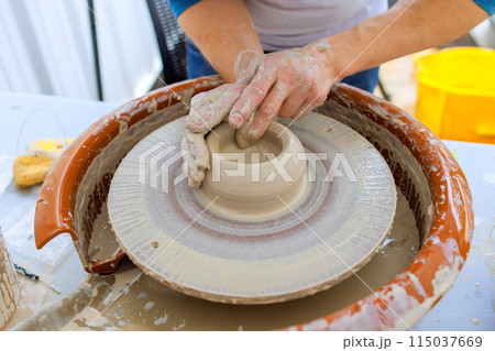 Worker creating bowl with wet soft clay using potter wheel Worker creating bowl with wet soft clay using potter wheel 115037669