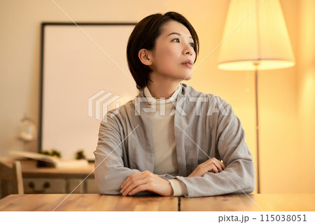 暖色の室内灯の部屋でリラックスした表情の女性 115038051
