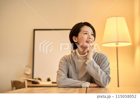 暖色の室内灯の部屋でリラックスした表情の女性 115038052