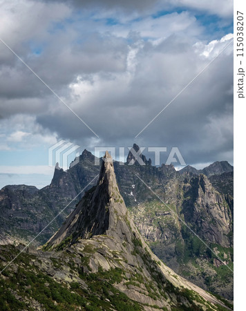 mountain silhouettes and large peaked top in rainy low stormy clouds 115038207