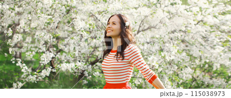 Lovely happy smiling young woman in spring blooming garden with flowers on the trees in park Lovely happy smiling young woman in spring blooming garden with flowers on the trees in park 115038973
