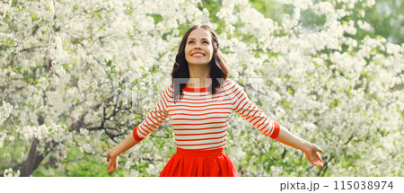 Lovely happy smiling young woman in spring blooming garden with flowers on the trees in park Lovely happy smiling young woman in spring blooming garden with flowers on the trees in park 115038974