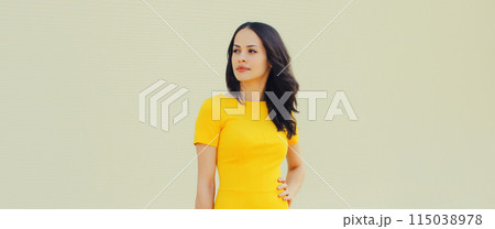 Portrait beautiful young brunette woman model posing in yellow dress looking away on gray background Portrait beautiful young brunette woman model posing in yellow dress looking away on gray background 115038978