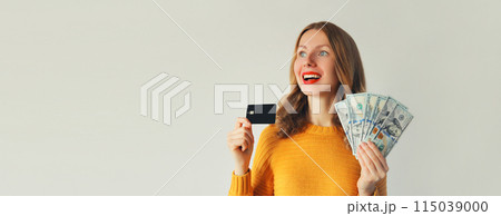 Happy young woman holding plastic credit bank card and cash money in dollar bills, looking away Happy young woman holding plastic credit bank card and cash money in dollar bills, looking away 115039000