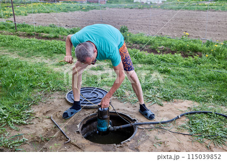 Submersible wastewater pump to pumping sewage containing fecal matter from septic tank in hands of man servicing well. 115039852