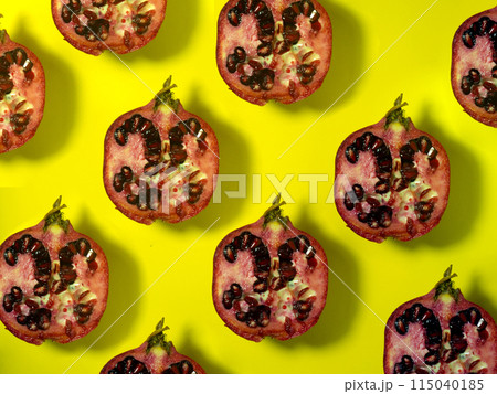 Background of pomegranate halves.Juicy fruit on a yellow background. Seeds inside the fruit. Raw food diet.  Sliced pomegranate 115040185