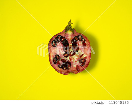 Half of pomegranate on yellow.Juicy fruit on yellow background. Sliced pomegranate. Vegan food. Raw food diet. 115040186