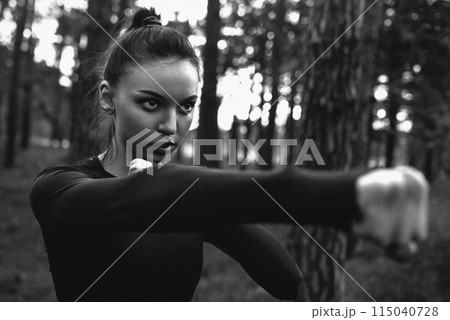 Black and white photo of a woman practicing martial arts in nature. film grain 115040728