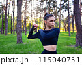 A young woman in a sports top warming up for a sport in the park. 115040731