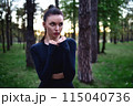 Young woman doing martial arts training in sporty black top holding hands in fighting pose against forest background. 115040736