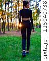 Shapely woman in black tight suit walking in nature in the woods in the sunlight. 115040738