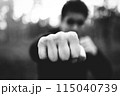 Close-up of a man's brutal fist striking a blow. criminal man striking a blow close-up. black and white filter, low key 115040739
