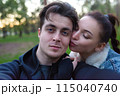 Selfies in nature of a loving couple man and woman. The woman kisses the man on the cheek. 115040740
