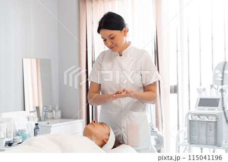 Dermatologist preparing to apply cream on woman's 115041196