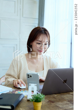 自宅でパソコンに向かって仕事をする女性デザイナー 115041352