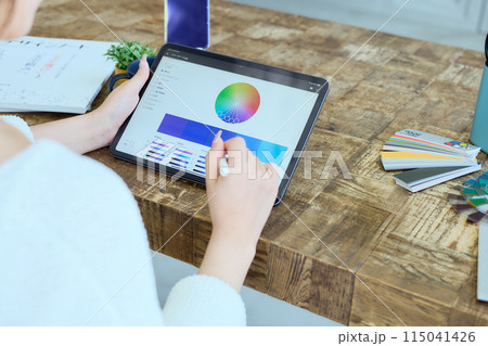 自宅でタブレットに向かって仕事をする女性デザイナー 自宅でタブレットに向かって仕事をする女性デザイナー 115041426