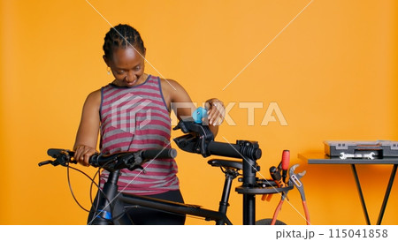 Engineer setting up bike repair stand, using it to adjust derailleur and cables, fixing broken wheels, studio background. Professional assembling workstand to maintain bicycle at eye level, camera B 115041858