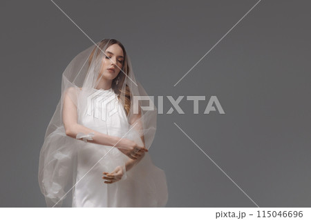 A woman in a wedding dress is holding a bouquet of flowers 115046696